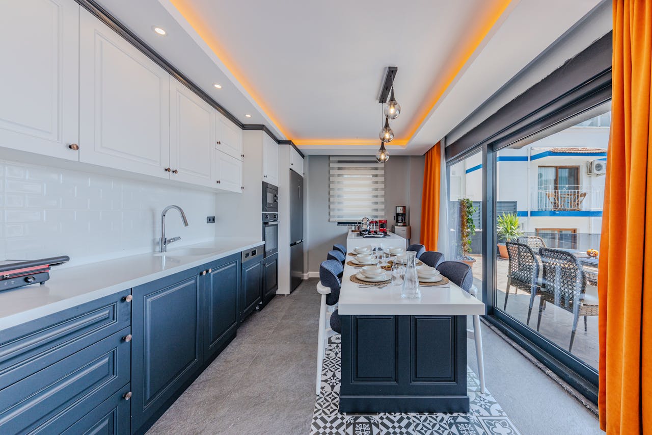 A kitchen with white cabinets and orange curtains